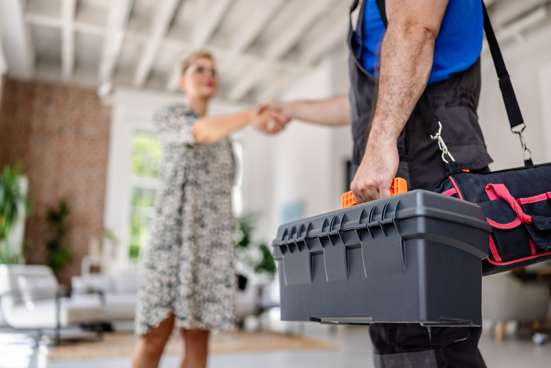 An HVAC technician shaking hands with a woman in her home