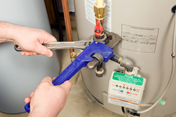 RS Andrews plumber using wrenches to repair a water heater in Chesapeake, VA, residential home.